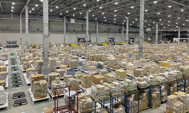 Consolidation warehouse floor stacked with shrink wrapped pallets of cartons under high bay lighting